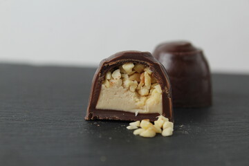 chocolate case candy in section with praline peanuts crushed on a gray background close-up. A day...
