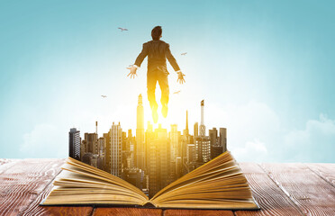 Businessman in suit running on top of a book