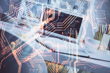 Computer on desktop in office with technology theme hologram. Double exposure. Tech concept.