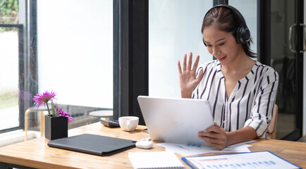 Happy asian woman young wearing headset, communicating with client via video computer call.