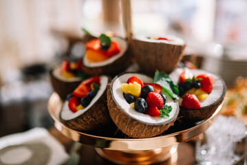 Healthy delicious dessert. in coconut bowl fruits, strawberry and blueberry and mint leaf