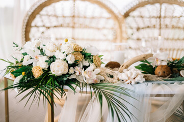 Straw chair and wedding table set decorated with flowers. Beautiful flower decoration of the wedding venue and ceremony, details