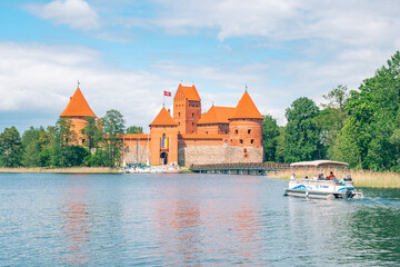 Naklejka na ściany i meble Trakai, Vilnius, Lithuania - June 3 2022: Medieval castle of Trakai, Vilnius, Lithuania, Eastern Europe, surrounded by beautiful lakes and nature in summer with wooden bridge, boats and tourists
