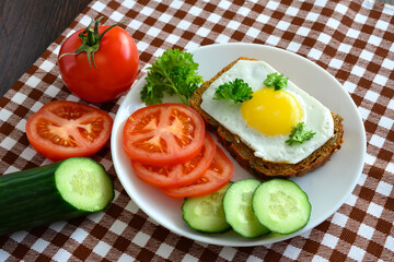 healthy sandwich on plate with fried egg, tomato and cucumber slices