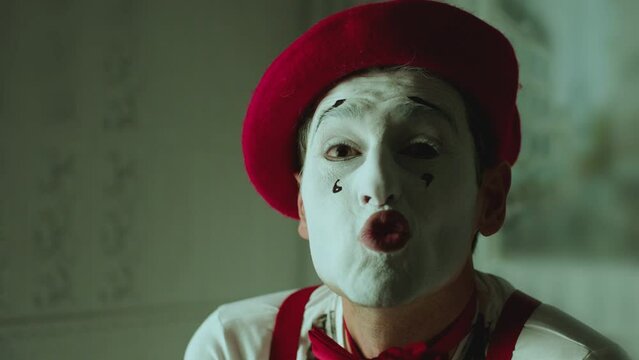 Close up portrait of french pantomime artist making different emotions and gestures of smile ,  closing one eye , sending air kiss, giving rose . White color makeup with tears .  Shot on ARRI camera  