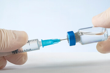 Vaccine in vial with punctured syringe on blue background
