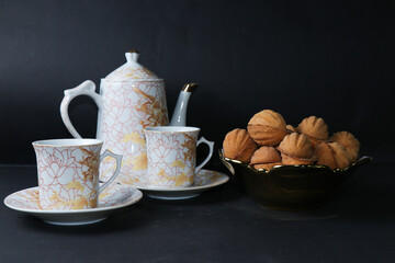 Tea set of cups, teapot and small saucers. Cookies on a saucer and cups with sweet tea