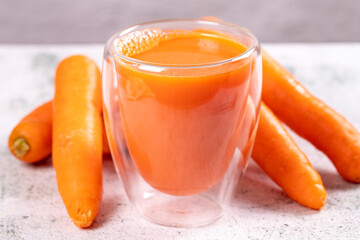 Carrot juice. Freshly squeezed juice. Freshly squeezed carrot juice in glass on stone background....
