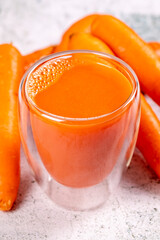 Carrot juice. Freshly squeezed juice. Freshly squeezed carrot juice in glass on stone background. Close-up