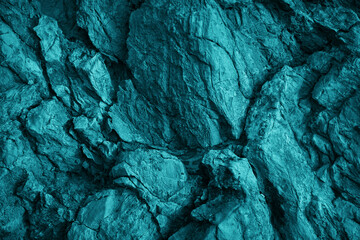 Blue green rock texture. Toned the rough surface of the mountain. Close-up. Dark teal stone background with space for design. Crushed, collapsed, crumbled.