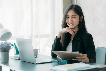 Businesswoman or accountant using the phone to check business information. Accounting Documents and Laptop Computer at Office Business Ideas