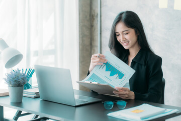 Businesswoman or accountant using the phone to check business information. Accounting Documents and Laptop Computer at Office Business Ideas