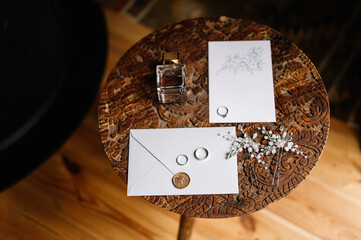 Bridal morning flat lay. Rings, silver jewellery in hair and wedding invitation on a wooden vintage chair.