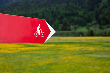 Red empty signboard with pointer and bicycle sign, on a green background