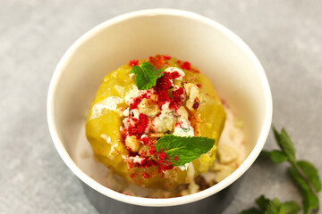 Baked apple with blue cheese, spices and nuts in a takeaway box  on a gray background. Healthy food delivery concept.