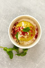 Baked apple with blue cheese, spices and nuts in a takeaway box  on a gray background. Healthy food delivery concept.