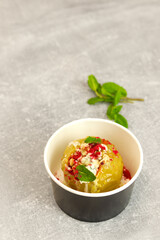 Baked apple with blue cheese, spices and nuts in a takeaway box  on a gray background. Healthy food delivery concept.