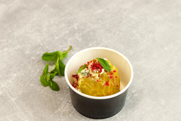 Baked apple with blue cheese, spices and nuts in a takeaway box  on a gray background. Healthy food delivery concept.