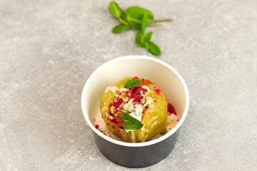 Baked apple with blue cheese, spices and nuts in a takeaway box  on a gray background. Healthy food delivery concept.