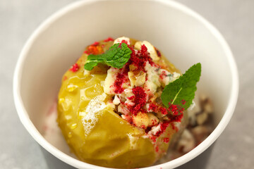 Baked apple with blue cheese, spices and nuts in a takeaway box  on a gray background. Healthy food delivery concept.
