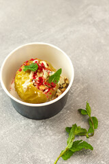 Baked apple with blue cheese, spices and nuts in a takeaway box  on a gray background. Healthy food delivery concept.
