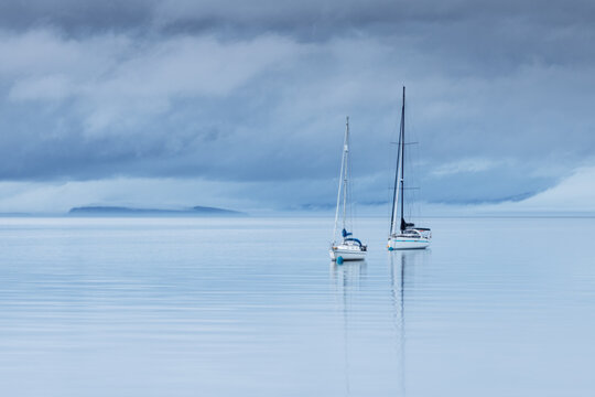 two sailboats anchored at low tide in blue hour in Brodick Bay, Isle of Arran, Scotland, United Kingdom