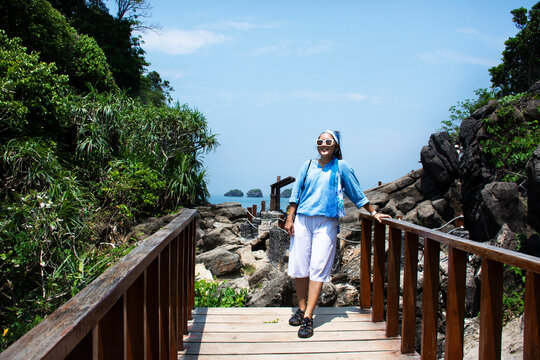 Travelers thai women travel walking relax and take photo on wooden bridge at Ao Toa Ba beach with unseen trip visit stone sea ​​heart in ocean in Pak Bara waterfront at La ngu city of Satun, Thailand