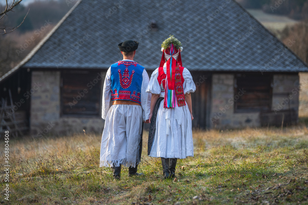 Wall mural a couple dressed in traditional folk costume. slovak costume in autumn nature. old country cottage i