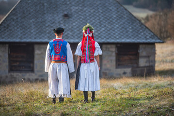 A couple dressed in traditional folk costume. Slovak costume in autumn nature. Old country cottage...