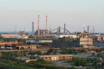Fototapeta na wymiar View on Port Marghera industrial part of Venice, Italy from container terminal during sunset. In horizon are factory chimneys and chemical factories.