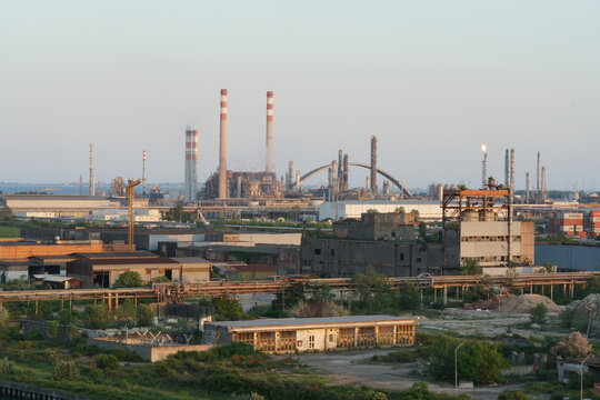 View on Port Marghera industrial part of Venice, Italy from container terminal during sunset. In horizon are factory chimneys and chemical factories.