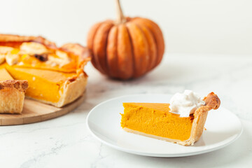 Cut slice of pumpkin pie close up on white background. Autumn orange cake