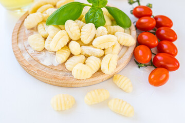 Ingredients for gnocchi including fresh gnocchi, tomatoes, olive oil, potatoes and basil