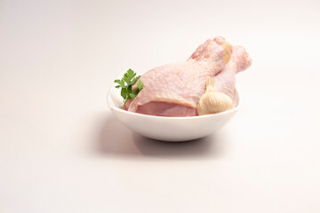 raw chicken legs in a plate on a white background