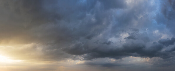Naklejka na ściany i meble Dramatic sunset sky with dark rainy clouds. Nature background. Sky panorama.
