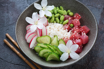 Middle close-up of hawaiian tuna poke bowl on a dark-grey stone surface, horizontal shot, selective focus