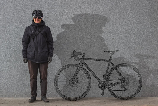 Cyclist with a painted road bicycle standing by the wall.