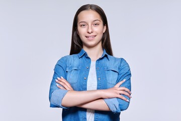 Portrait of smiling beautiful teenage girl looking at camera on light background