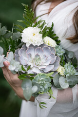 Lush girl in a white wedding dress. Stylish charming and cheerful bride. Green park with light bulbs in the background. Wedding bouquet. Flowers close-up.