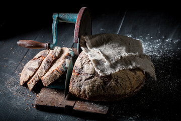 Homemade loaf of bread on slicer with crumbs and flour