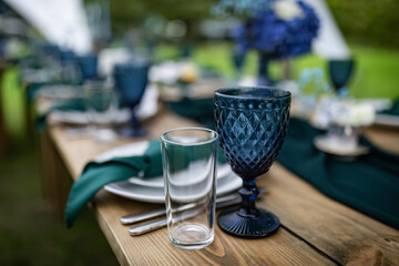 Wedding decorations, long wooden table setting. Glasses and plates. Beautiful park