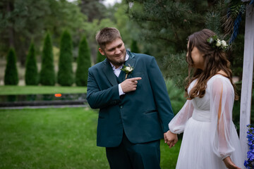 Curvy people, wedding couple on a walk. Stylish charming bride, groom in green suit. Beautiful park