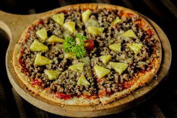 Top view. Pizza topped with meat, pineapple and sauce.
