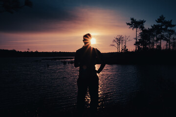 Silhouette of a lonely man standing by the river watch the sun go down , Rear view , , Phu Kradueng National Park ,Thailand