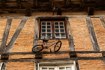 Ventana de madera en fachada de ladrillo antigua con bicicleta decorándola.