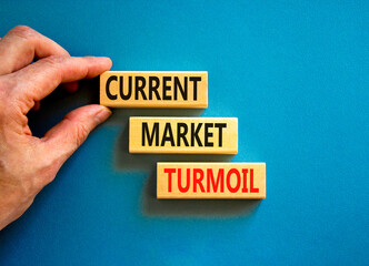 Current market turmoil symbol. Concept words Current market turmoil on wooden blocks on a beautiful blue table blue background. Businessman hand. Business, finacial current market turmoil concept.