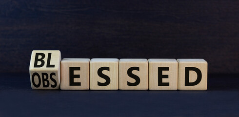 Blessed or obsessed symbol. Turned wooden cubes and changed the concept word Obsessed to Blessed. Beautiful black table black background. Business blessed or obsessed concept. Copy space.