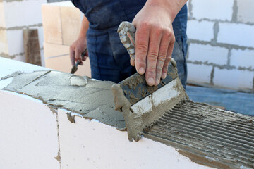 The bricklayer applies the adhesive before stealing the bricks or building blocks. The concept of...