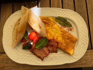 omelette with bacon and bread on a white plate