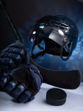 Closeup of ice hockey equipment against a dark background. Ice hockey helmet, stick, puck and gloves